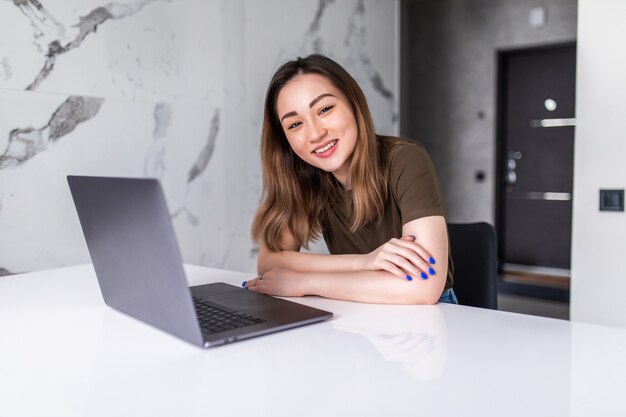 Junge schöne Asiatin mit Laptop in der Küche