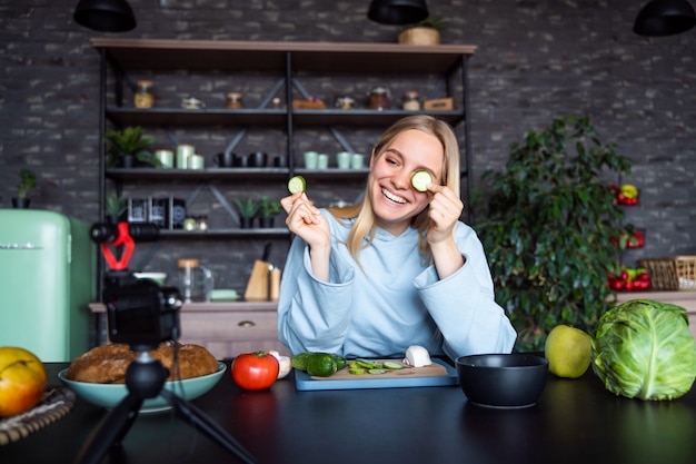 Junge schöne Blondine nimmt Videos auf, während sie in der Küche kocht