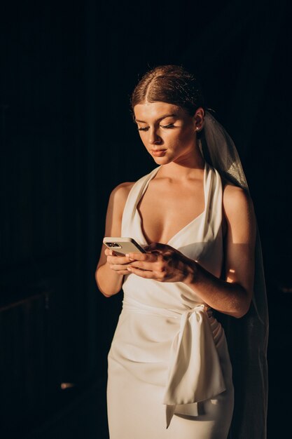 Junge schöne Braut mit Telefon auf Hochzeit