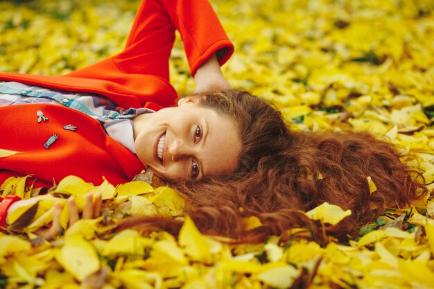 Junge schöne Dame umgab Herbstlaub