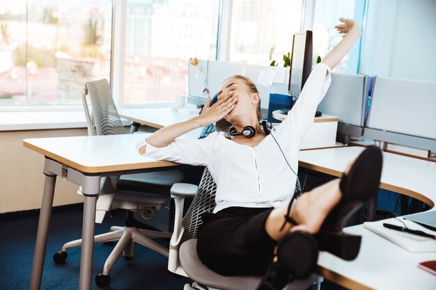 Junge schöne erfolgreiche Geschäftsfrau, die sich am Arbeitsplatz, im Büro ausruht