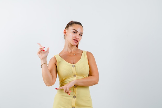 Junge schöne Frau, die auf die obere linke Ecke im Kleid zeigt und freudlos aussieht. Vorderansicht.