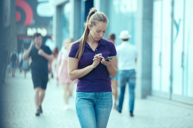 Junge schöne Frau, die auf Handy im Freien spricht.