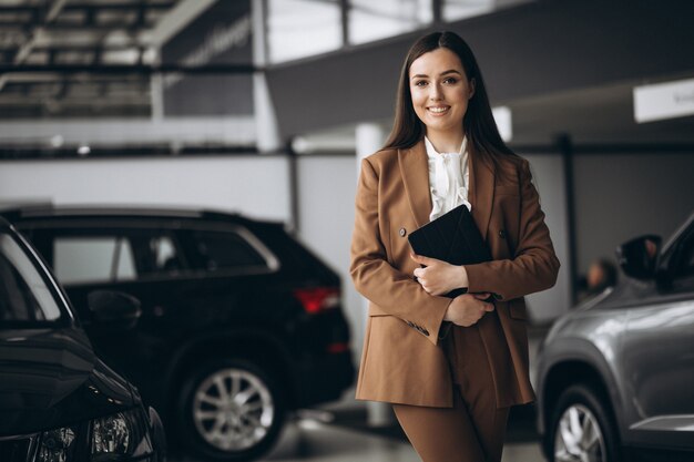 Junge schöne Frau, die Auto in einem Autoausstellungsraum wählt