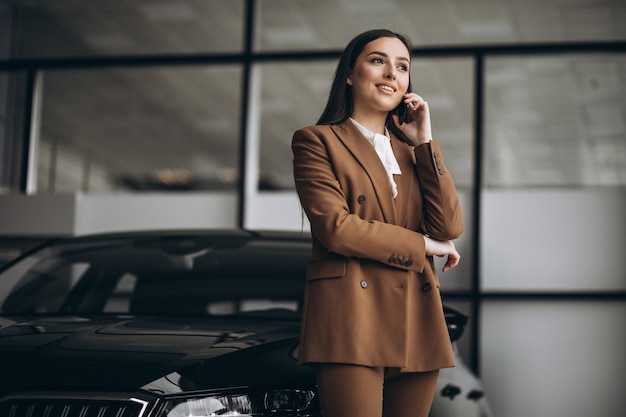 Junge schöne Frau, die Auto in einem Autoausstellungsraum wählt