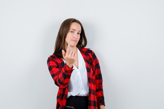 Junge schöne Frau, die einlädt, in lässigem Outfit zu kommen und selbstbewusst auszusehen. Vorderansicht.