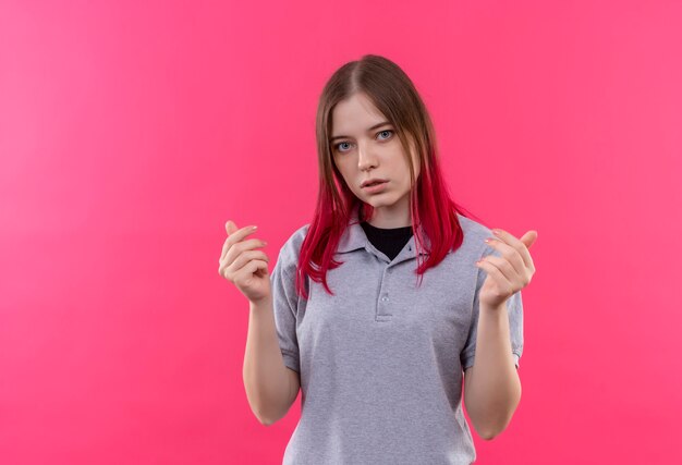 junge schöne Frau, die graues T-Shirt trägt, das Hände auf isolierter rosa Wand mit Kopienraum anhebt