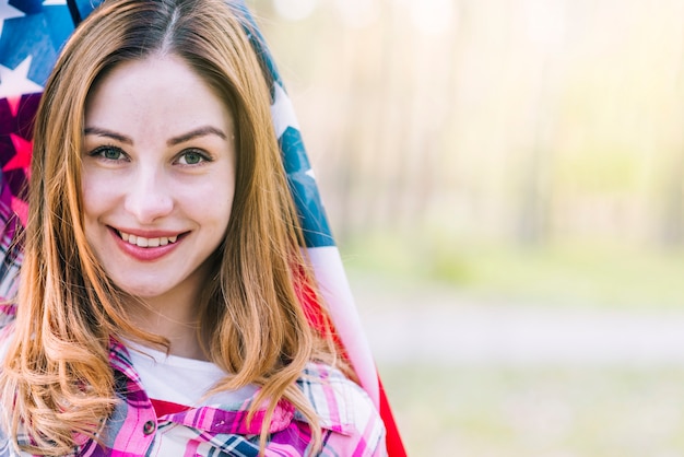 Kostenloses Foto junge schöne frau, die in usa-flagge einwickelt