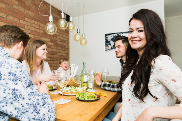 Junge schöne Frau, die mit Freunden sitzt