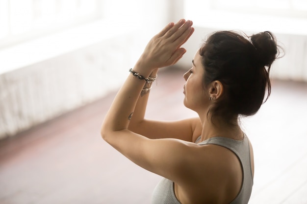 Junge schöne Frau, die namaste Geste, Dachbodenstudio macht