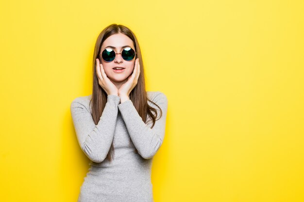 Junge schöne Frau, die Sommerart und Sonnenbrille über gelbe isolierte Wand trägt, die Mund mit Hand mit schmerzhaftem Ausdruck wegen Zahnschmerzen berührt