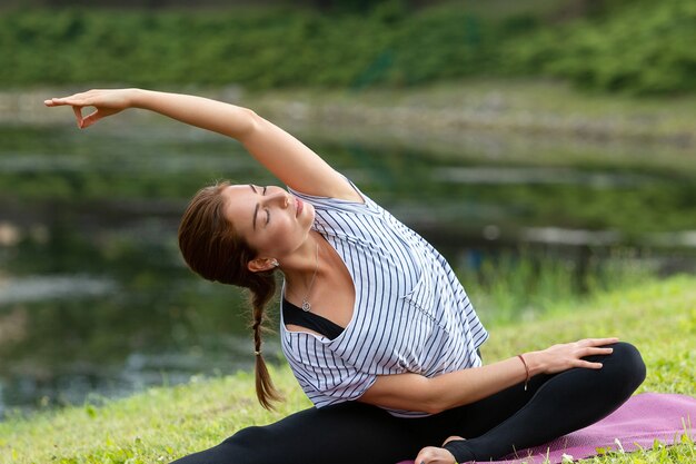 Junge schöne Frau, die Yoga-Übung im grünen Park tut. Gesundes Lebensstil- und Fitnesskonzept.