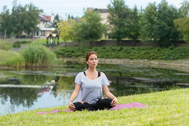 Junge schöne Frau, die Yoga-Übung im grünen Park tut. Gesundes Lebensstil- und Fitnesskonzept.