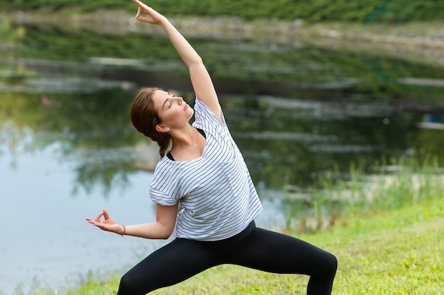 Junge schöne Frau, die Yoga-Übung im grünen Park tut