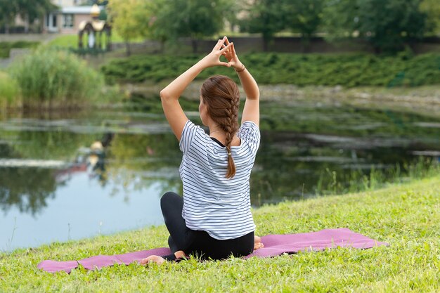 Junge schöne Frau, die Yoga-Übung im grünen Park tut