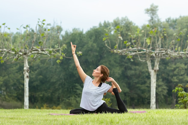 Junge schöne Frau, die Yogaübung im Freien tut
