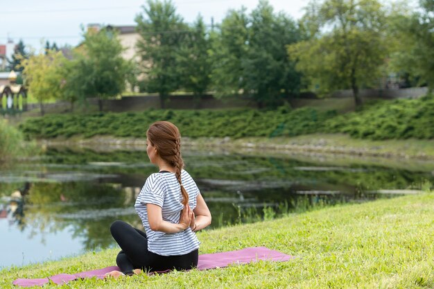 Junge schöne Frau, die Yogaübung im grünen Park tut