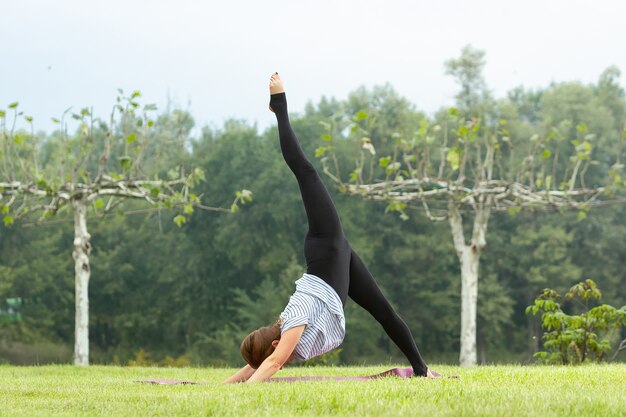 Junge schöne Frau, die Yogaübung im grünen Park tut