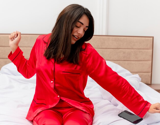 Junge schöne Frau im roten Schlafanzug, der im Bett entspannt