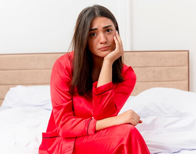 Junge schöne Frau im roten Schlafanzug, der im Bett entspannt