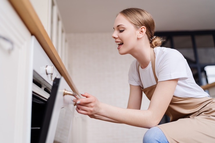 Kostenlose Foto junge schöne frau in der küche beim backen einer schürze