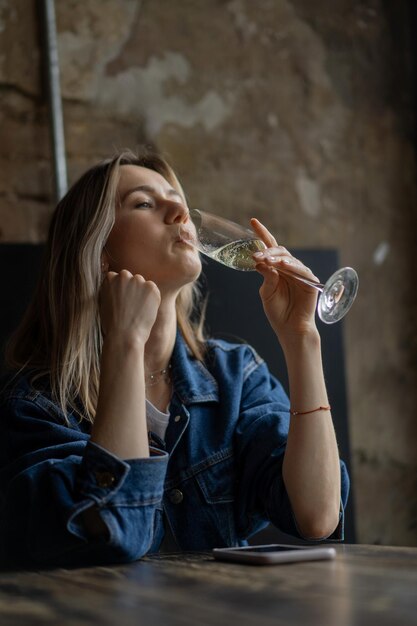 Junge schöne Frau in einem Café, eine Frau, die Champagner in einem Café trinkt und redet.