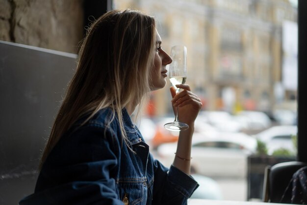 Junge schöne Frau in einem Café, eine Frau, die Champagner in einem Café trinkt und redet.