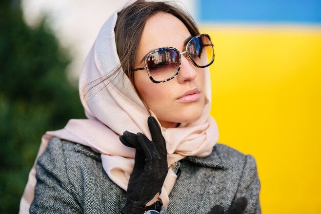 Junge schöne Frau in einem Mantel, der auf einer Bank im Park sitzt