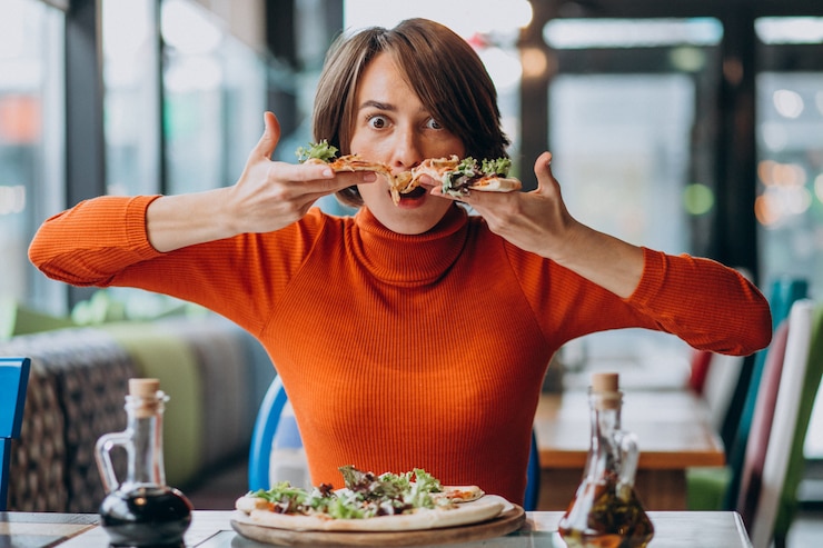 Kostenlose Foto junge schöne frau isst pizza in einer pizza-bar