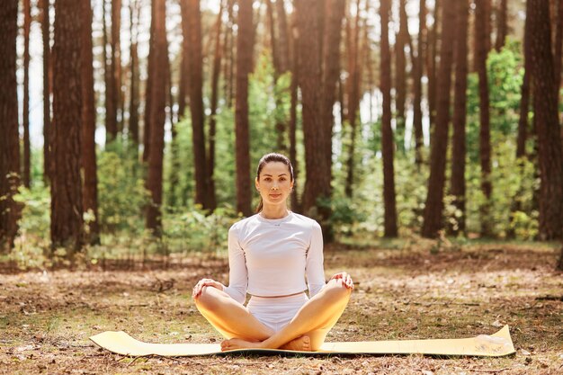 Junge schöne Frau mit angenehmem Aussehen sitzt auf Karemat in Yoga-Posemat