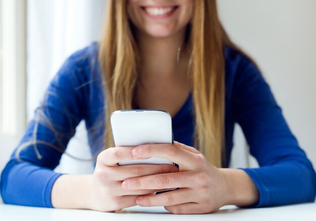 Junge schöne Frau mit ihrem Handy zu Hause.