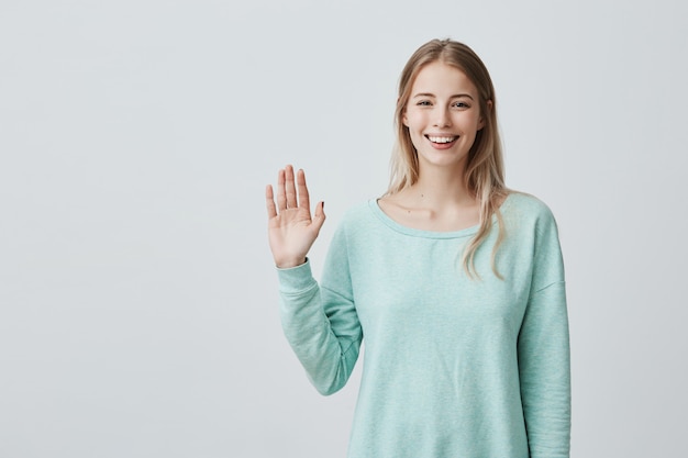 Junge schöne Frau mit langen blonden Haaren, die Hallo sagen