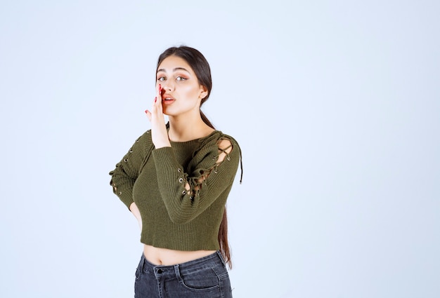 junge schöne Frau Modell flüstern etwas beim Blick in die Kamera.