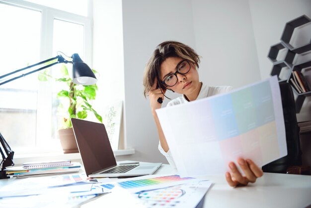 Junge schöne Geschäftsfrau, die am Arbeitsplatz im Büro sitzt.