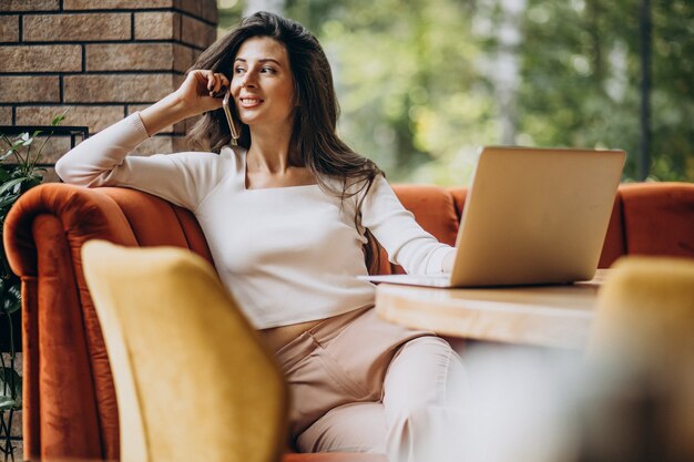 Junge schöne Geschäftsfrau, die am Computer in einem Café arbeitet