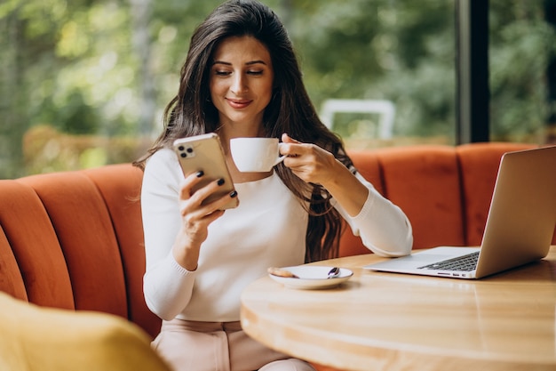 Junge schöne geschäftsfrau, die am computer in einem café arbeitet