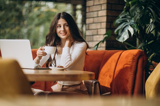 Junge schöne Geschäftsfrau, die am Computer in einem Café arbeitet