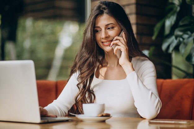 Junge schöne Geschäftsfrau, die am Computer in einem Café arbeitet