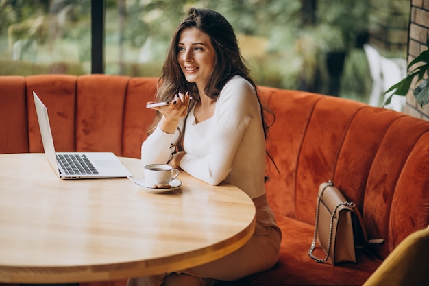 Junge schöne Geschäftsfrau, die am Computer in einem Café arbeitet