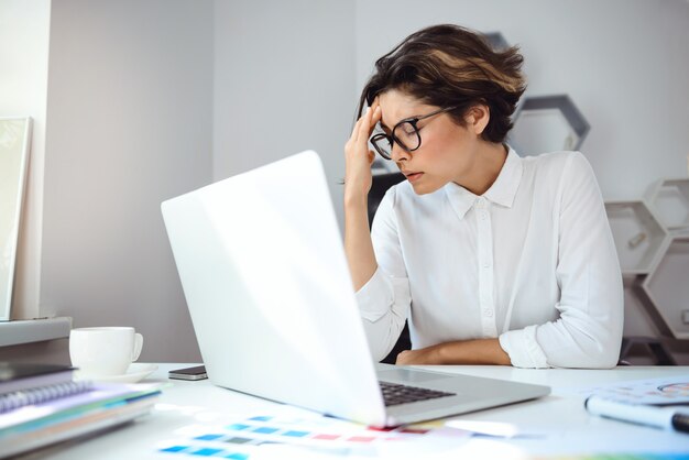 Junge schöne Geschäftsfrau, die mit Laptop am Arbeitsplatz im Büro arbeitet.