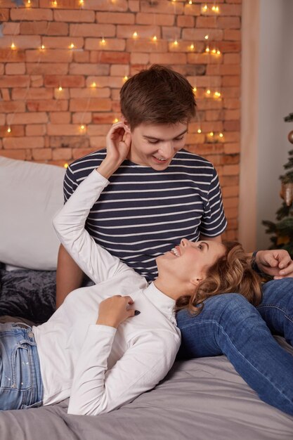 Junge schöne glückliche freundin, die auf den knien ihres freundes liegt, sie genießen diesen moment zusammen. der mann, der ihre freundin hält, schaut sie an