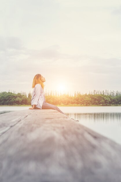 Junge schöne Hippie-Frau, die auf dem See sitzt entspannt mit