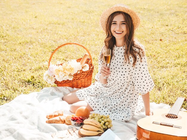 Junge schöne Hippie-Frau im trendigen Sommerkleid und Hut. Sorglose Frau, die draußen Picknick macht.