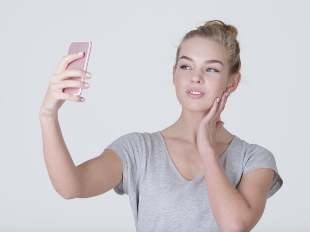 Junge schöne kaukasische Mädchen macht Selfies. Glückliche wundervolle Frau mit Handy in Händen