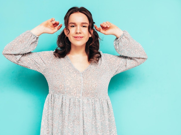 Junge schöne lächelnde Frau im trendigen Sommerkleid Sexy sorglose Frau posiert in der Nähe der blauen Wand im Studio Positives Modell, das Spaß hat Fröhlich und glücklich