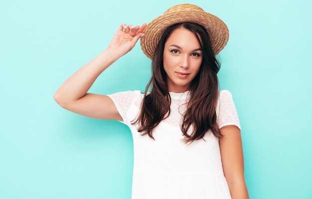 Junge schöne lächelnde Frau in trendiger Sommerkleidung Sexy sorglose Frau posiert in der Nähe der Wand im Studio Positives brünettes Modell, das Spaß hat Fröhlich und glücklich In Hut