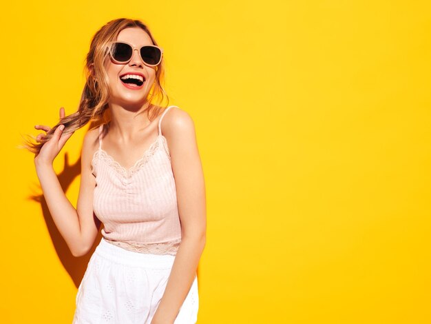 Junge schöne lächelnde Frau in trendiger Sommerkleidung Sexy sorglose Frau posiert in der Nähe von blau gelb im Studio Positives Modell, das Spaß hat Fröhlich und glücklich In Sonnenbrillen Schreiend und schreiend