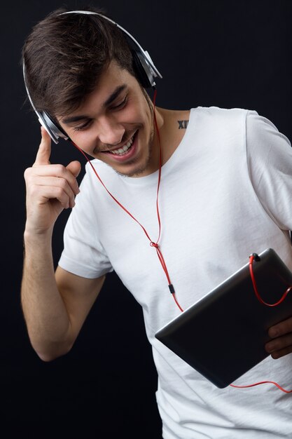 Junge schöne Mann Musik hören. Isoliert auf schwarz.