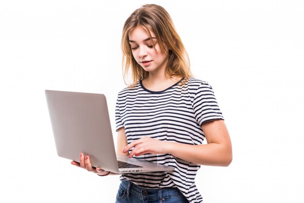 Junge schöne moderne Frau, die einen Laptop in den Händen, die sich auf eine weiße Wand stützt