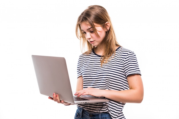 Junge schöne moderne Frau, die einen Laptop in den Händen, die sich auf eine weiße Wand stützt